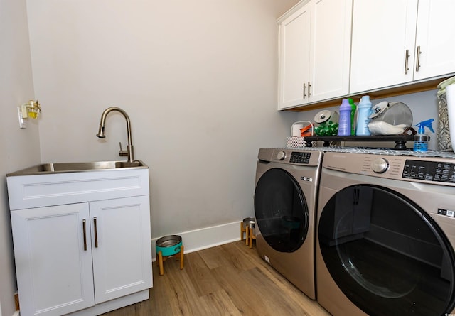 402 Bumble Cir, Murrells Inlet, SC 29576 - clothes washing area featuring baseboards, washer and clothes dryer, cabinet space, a sink, and light wood finished floors