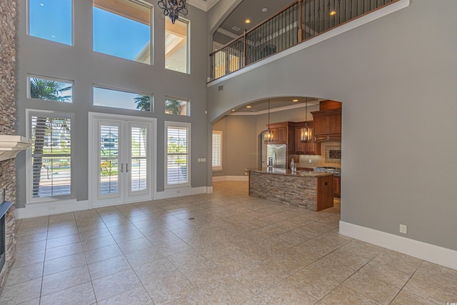 5208 Nightingale Dr, Myrtle Beach, SC 29577 - unfurnished living room featuring a towering ceiling, arched walkways, light tile patterned flooring, baseboards, and a fireplace