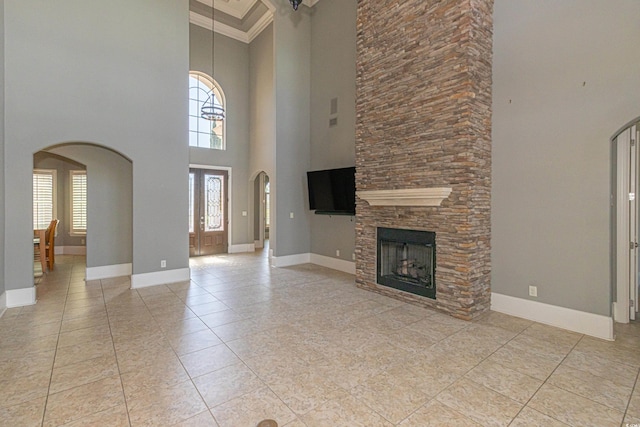 5208 Nightingale Dr, Myrtle Beach, SC 29577 - unfurnished living room with a towering ceiling, arched walkways, baseboards, a fireplace, and light tile patterned floors