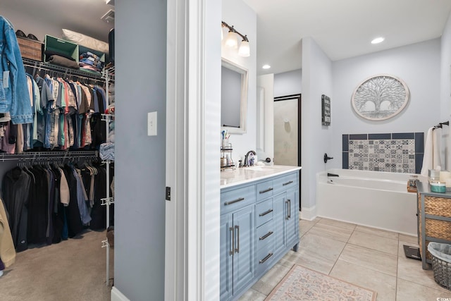 full bathroom with recessed lighting, vanity, a walk in closet, baseboards, and a garden tub