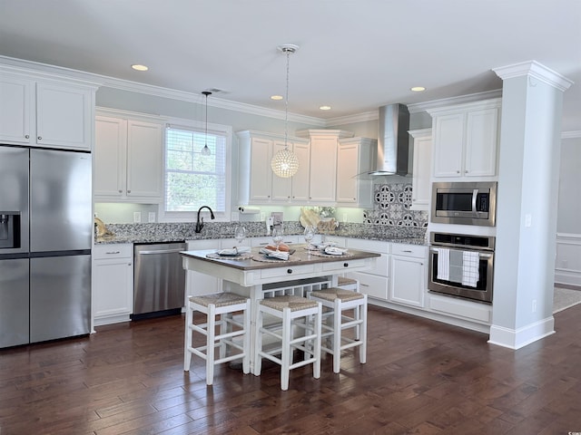 712 Crystal Water Way, Myrtle Beach, SC 29579 - kitchen featuring appliances with stainless steel finishes, wall chimney range hood, a breakfast bar, white cabinetry, and ornamental molding