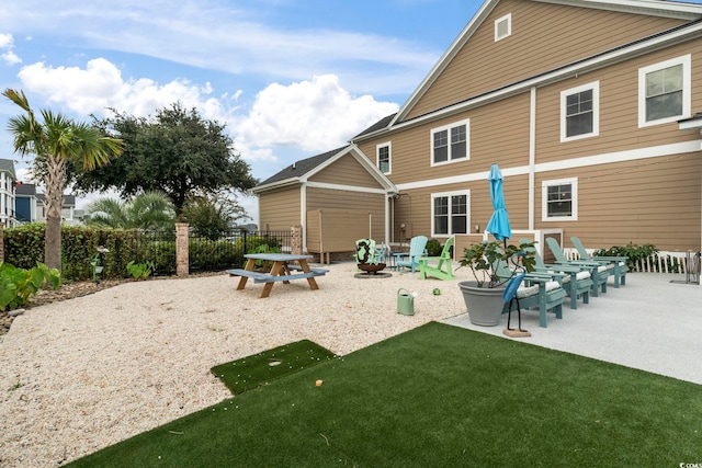 back of house featuring fence, a fire pit, a yard, and a patio area