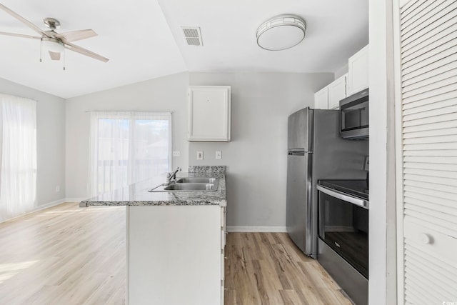 kitchen with a sink, light wood-type flooring, appliances with stainless steel finishes, and baseboards