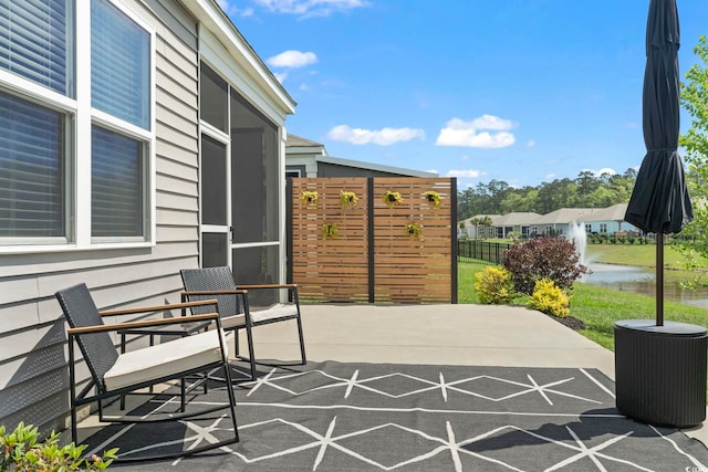 view of patio with fence and a water view