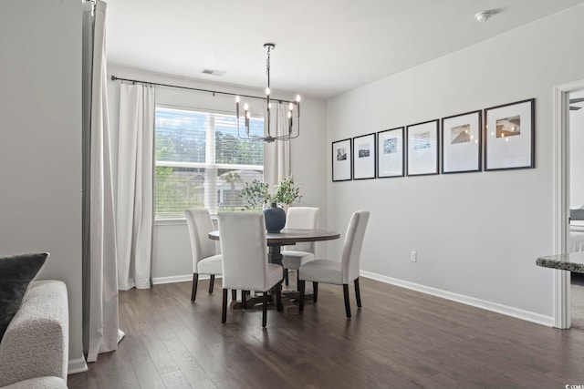 dining space featuring a chandelier, baseboards, and dark wood finished floors