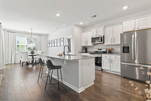 kitchen with stainless steel appliances, a sink, white cabinetry, dark wood-style flooring, and an island with sink