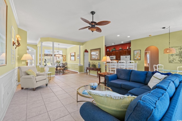 living area with decorative columns, a ceiling fan, arched walkways, light tile patterned floors, and recessed lighting