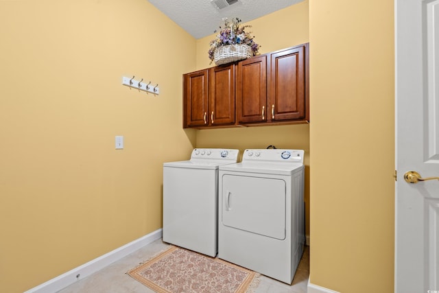 clothes washing area with light tile patterned flooring, baseboards, a textured ceiling, cabinet space, and independent washer and dryer