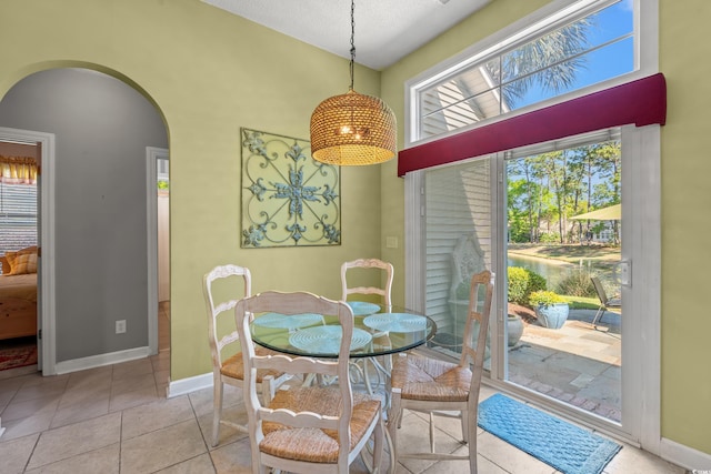 dining area with arched walkways, baseboards, and tile patterned flooring
