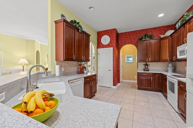kitchen featuring light countertops, arched walkways, and white appliances