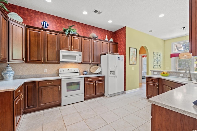 kitchen with visible vents, a sink, white appliances, light countertops, and arched walkways