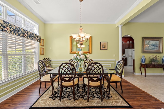 dining space with an inviting chandelier, visible vents, ornamental molding, baseboards, and arched walkways
