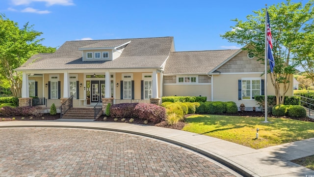 view of front of house with a porch, curved driveway, a shingled roof, and a front lawn