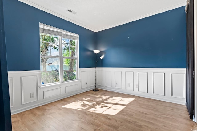 405 Emerson Dr, Myrtle Beach, SC 29579 - empty room featuring crown molding, visible vents, a wainscoted wall, and light wood-type flooring