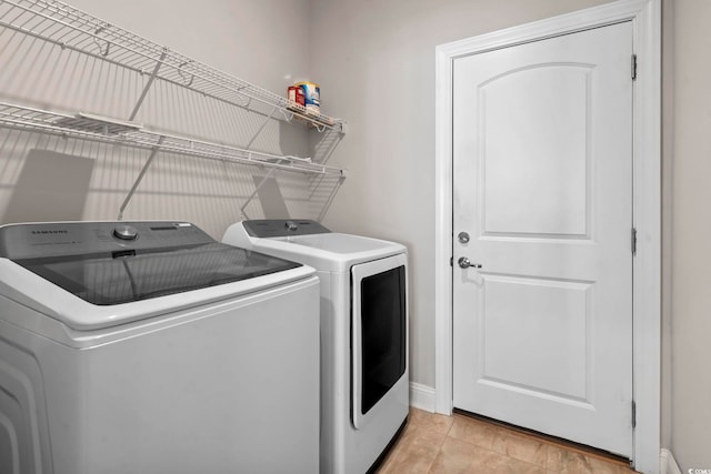 washroom with independent washer and dryer, baseboards, and light tile patterned floors