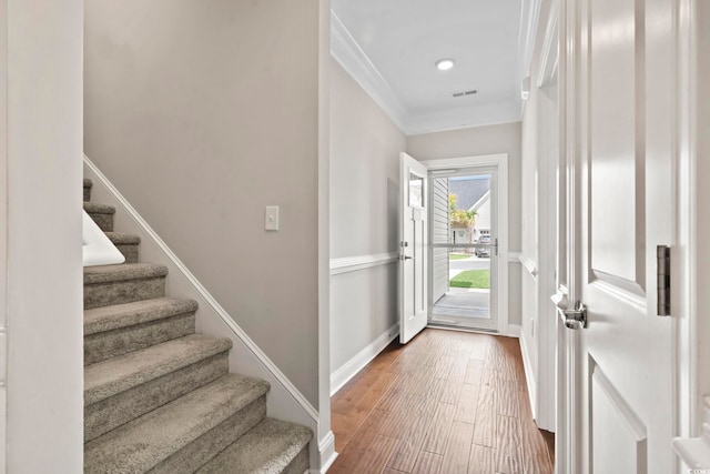 foyer with crown molding, wood finished floors, baseboards, and stairs