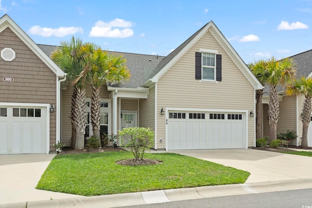 traditional-style home featuring driveway, a front yard, a garage, and roof with shingles