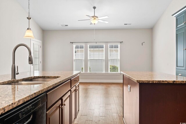 kitchen featuring black dishwasher, a sink, a ceiling fan, light wood-style flooring, and decorative light fixtures