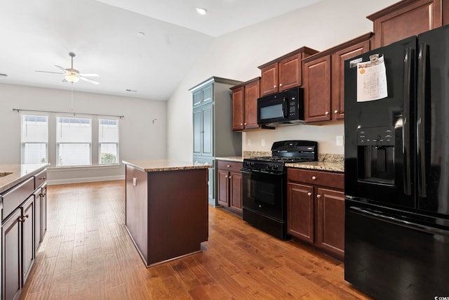 kitchen with black appliances, a ceiling fan, vaulted ceiling, dark wood finished floors, and light stone countertops