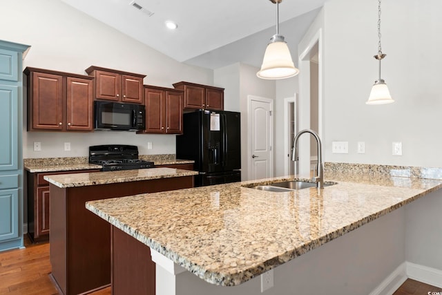 kitchen with black appliances, a sink, a peninsula, wood finished floors, and light stone countertops