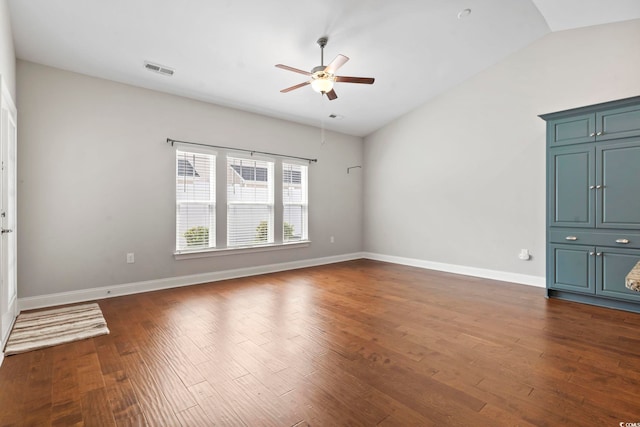 unfurnished room with vaulted ceiling, a ceiling fan, dark wood-type flooring, and baseboards