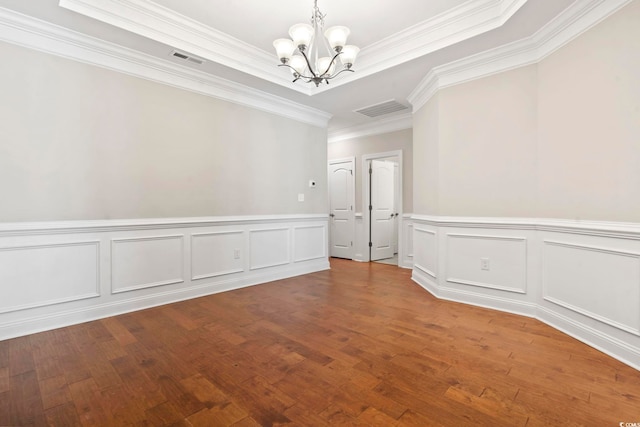 spare room with a chandelier, crown molding, a decorative wall, wood finished floors, and wainscoting
