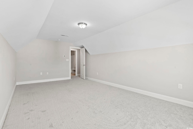 additional living space with vaulted ceiling, light carpet, and baseboards