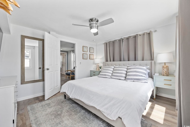 bedroom with a ceiling fan, baseboards, and wood finished floors
