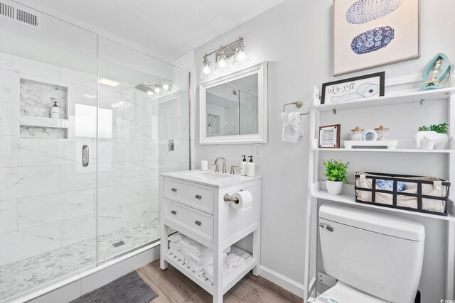 bathroom with visible vents, a stall shower, wood finished floors, vanity, and toilet