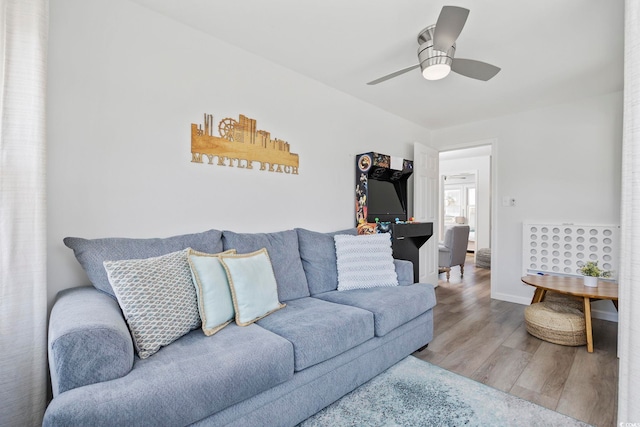 living area with baseboards, a ceiling fan, and wood finished floors
