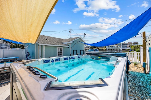 view of pool featuring a hot tub and fence