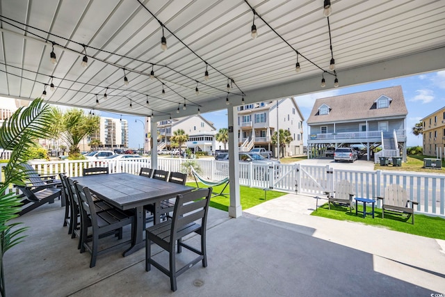 view of patio / terrace with a gate, fence, a residential view, and outdoor dining space