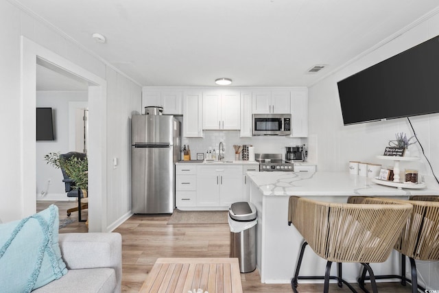 kitchen with visible vents, ornamental molding, white cabinets, and stainless steel appliances