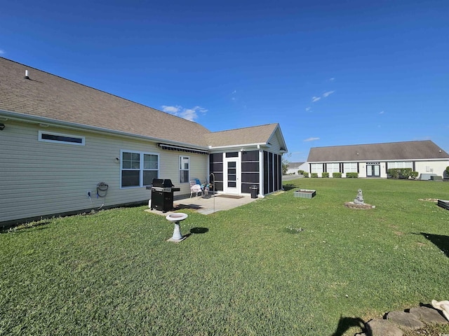back of property with a patio, a yard, a sunroom, and roof with shingles