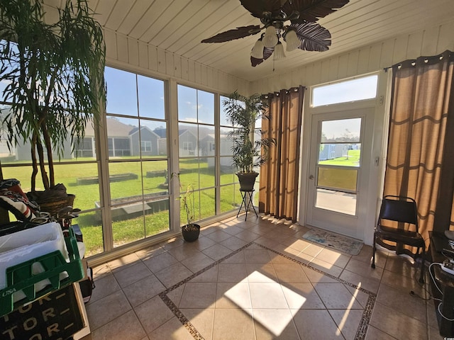 sunroom / solarium with a residential view and a ceiling fan