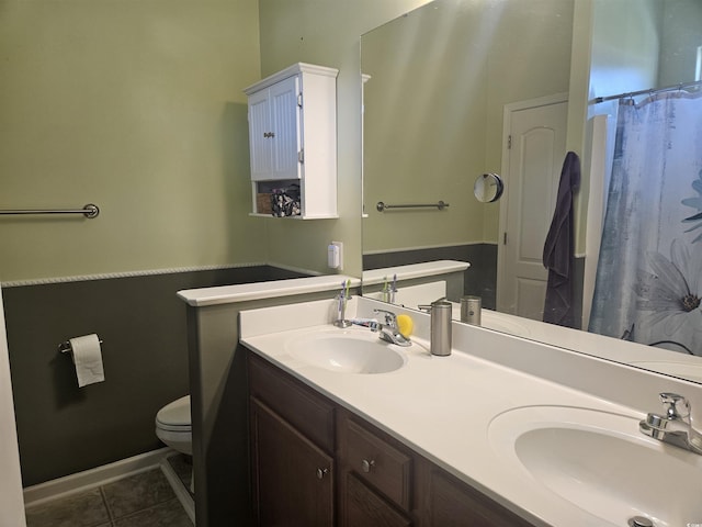 full bathroom featuring tile patterned floors, toilet, double vanity, and a sink