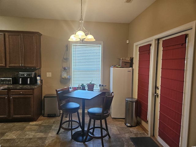 dining area featuring stone finish floor and a chandelier