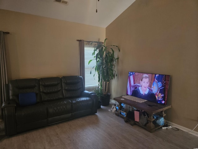 living area featuring wood finished floors, visible vents, vaulted ceiling, and baseboards