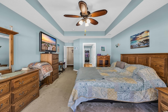 bedroom featuring light carpet, a raised ceiling, a ceiling fan, and baseboards
