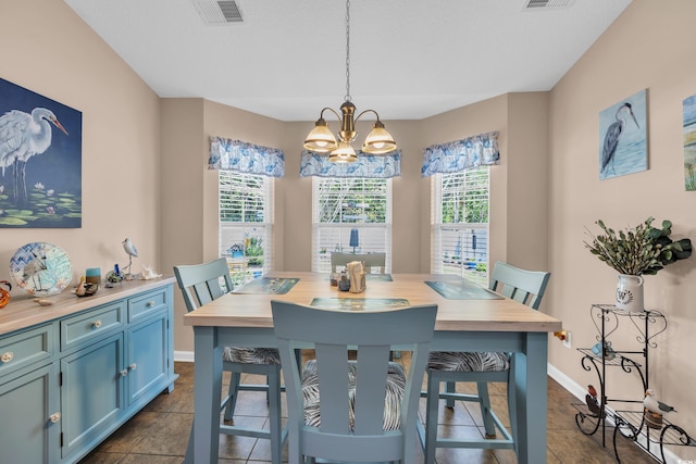 dining room with a chandelier, baseboards, and dark tile patterned flooring