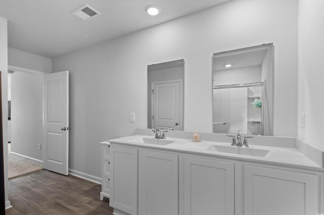 full bathroom featuring a sink, double vanity, wood finished floors, and visible vents