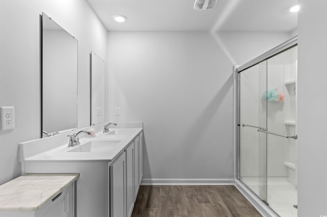 full bath with a sink, double vanity, a stall shower, and wood finished floors