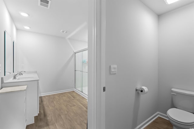 bathroom with vanity, toilet, wood finished floors, visible vents, and a stall shower