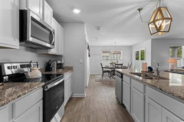 kitchen featuring a sink, stainless steel appliances, baseboards, visible vents, and dark wood-style floors