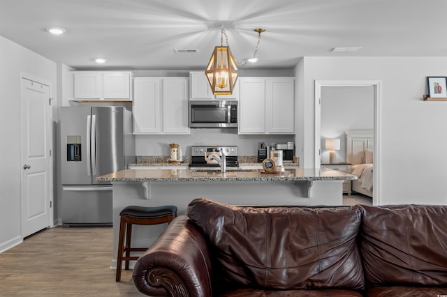 kitchen with visible vents, open floor plan, stone counters, and stainless steel appliances