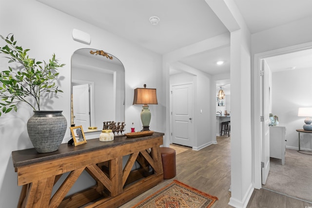 hallway featuring arched walkways, baseboards, and wood finished floors