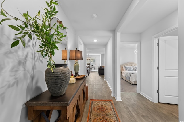hall featuring baseboards, recessed lighting, and wood finished floors