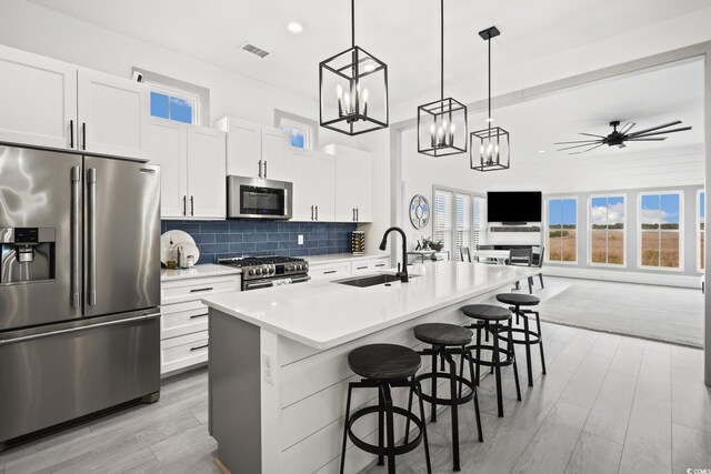 35 Red Skiff Ln Unit 35, Pawleys Island, SC 29585 - kitchen featuring appliances with stainless steel finishes, a sink, light wood-type flooring, a breakfast bar area, and decorative backsplash