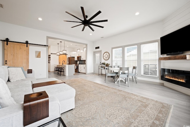35 Red Skiff Ln Unit 35, Pawleys Island, SC 29585 - living area with a barn door, a ceiling fan, light wood-type flooring, a glass covered fireplace, and recessed lighting