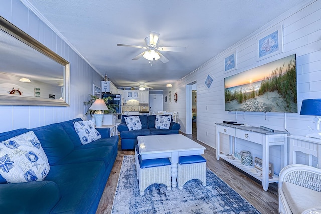 living area with crown molding, ceiling fan, and wood finished floors